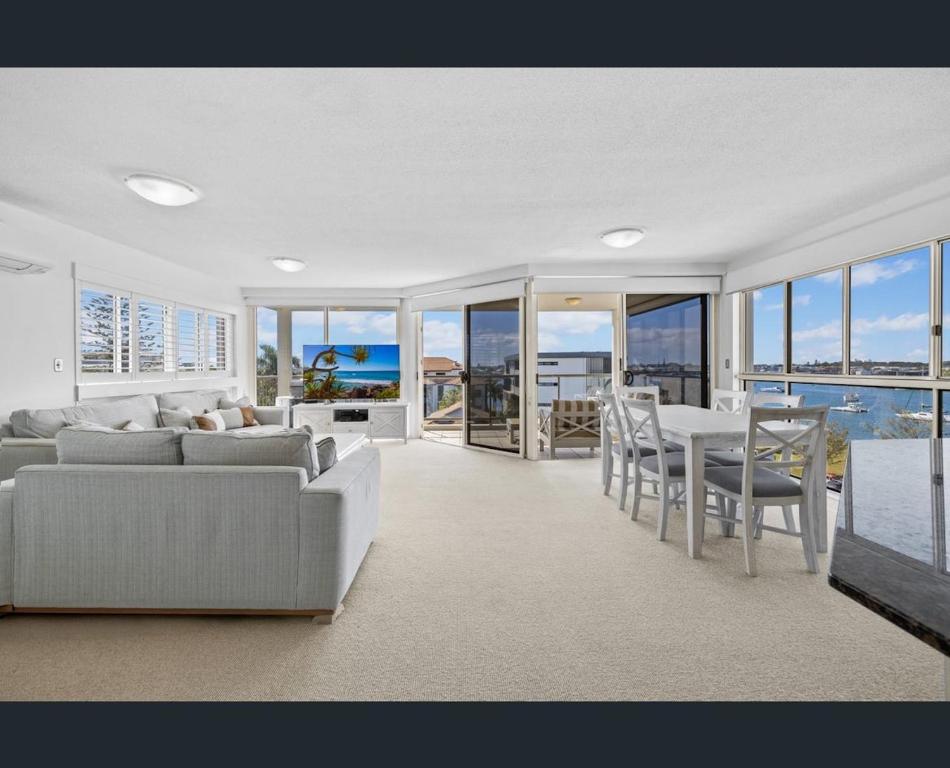 a living room with a couch and a table and chairs at Walk to Beach • Luxury Waterfront Penthouse in Mooloolaba