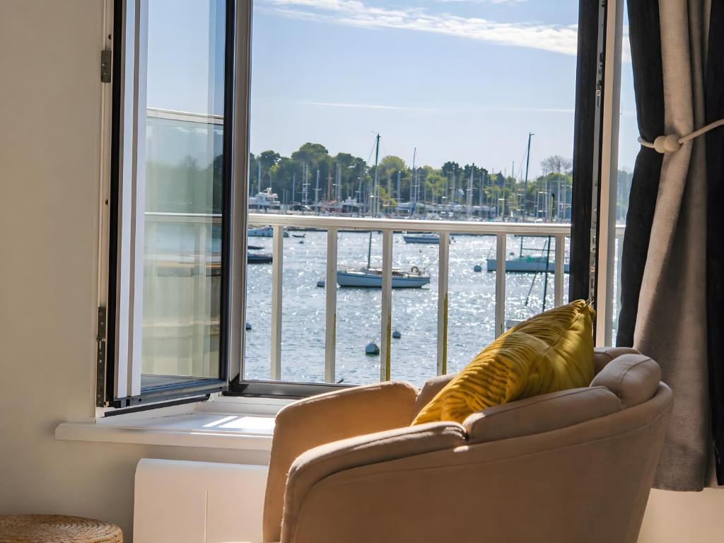 a living room with a chair and a view of a harbor at Le nid des Perdrix in Île-Tudy