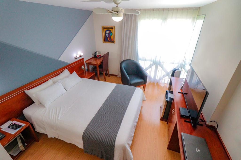a bedroom with a bed and a desk with a television at Hotel Boutique Runcu Miraflores in Lima