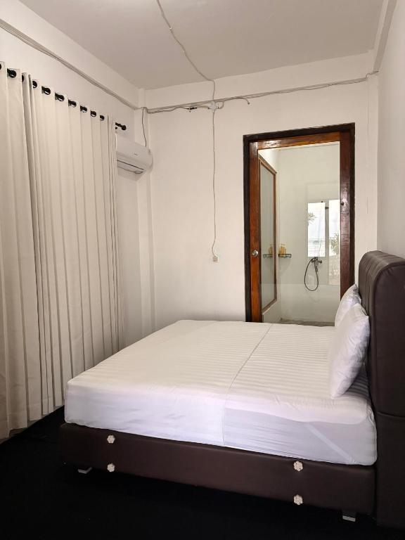 a bedroom with a white bed and a mirror at Queen house in Waikabubak