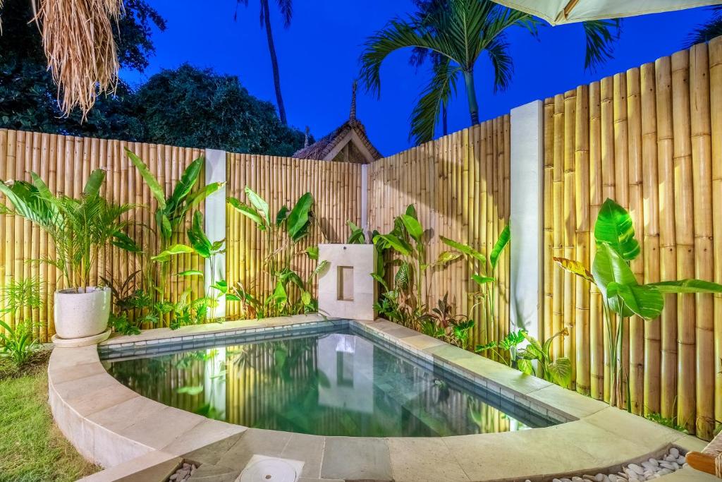 a swimming pool in front of a wooden fence at Villa Anak Ikan in Gili Islands
