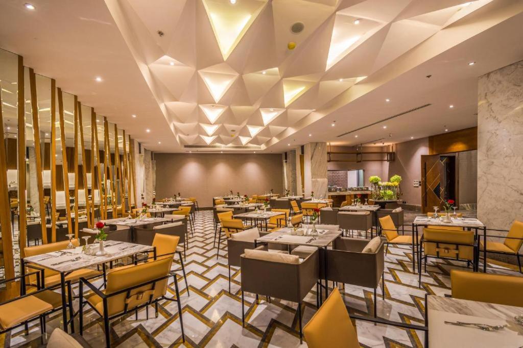 a dining room with tables and yellow chairs at Oscar Apartments in Cairo