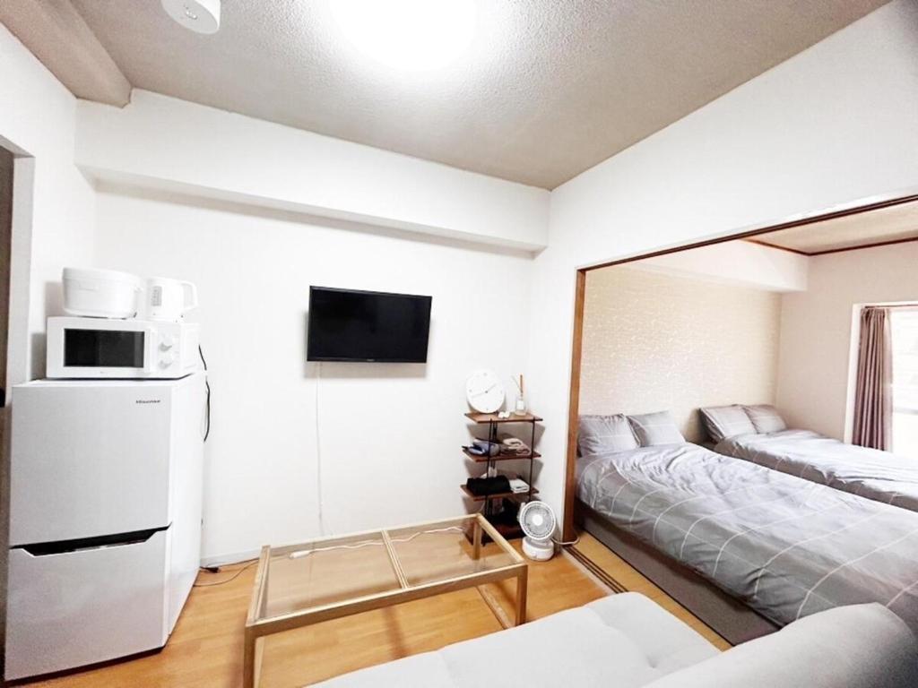 a small living room with a bed and a microwave at Crest YS chiyoda 4B in Aoichō