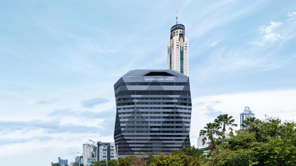 a tall building with a sign on top of it at Queensland Hotel Bangkok in Bangkok