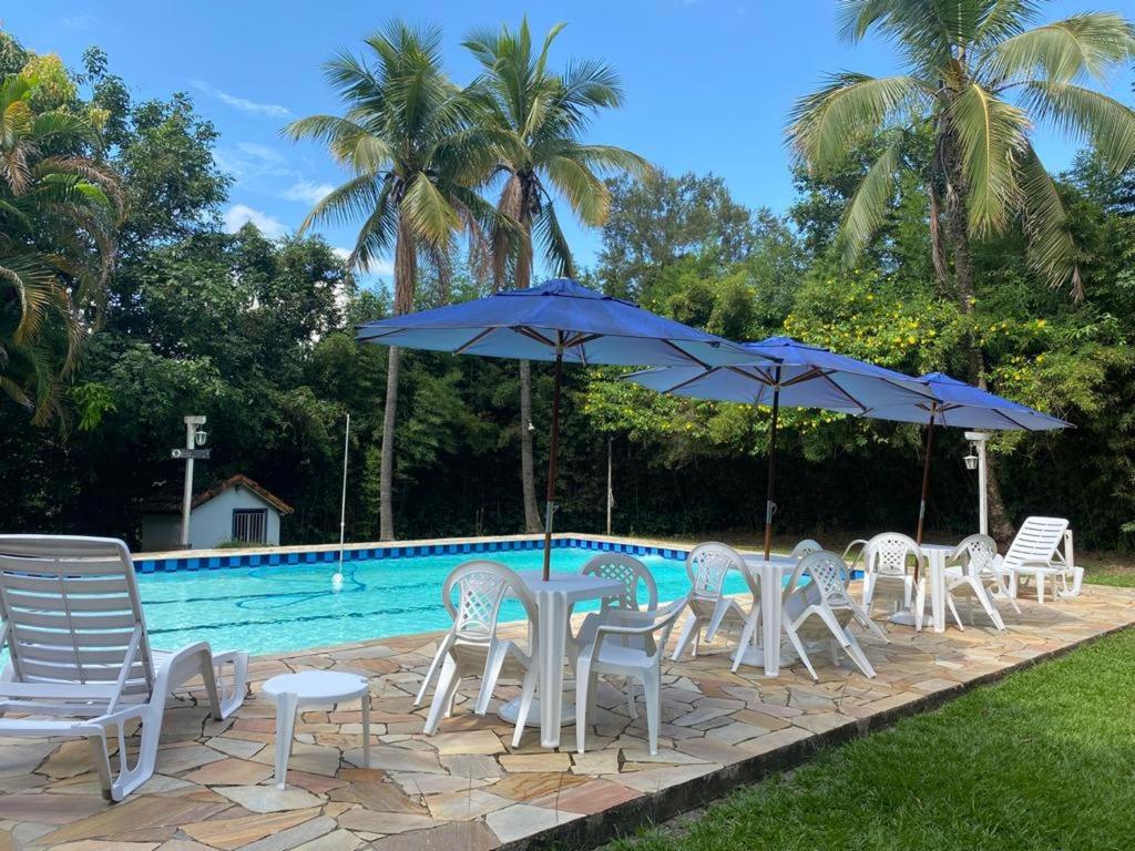 a group of chairs and umbrellas next to a pool at Pousada Ypê Amarelo in Itatiaia