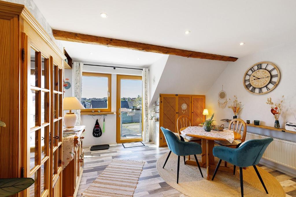 a dining room with a table and chairs and a clock at Fewo Sonnenstübchen Mendig 2Pers in Mendig