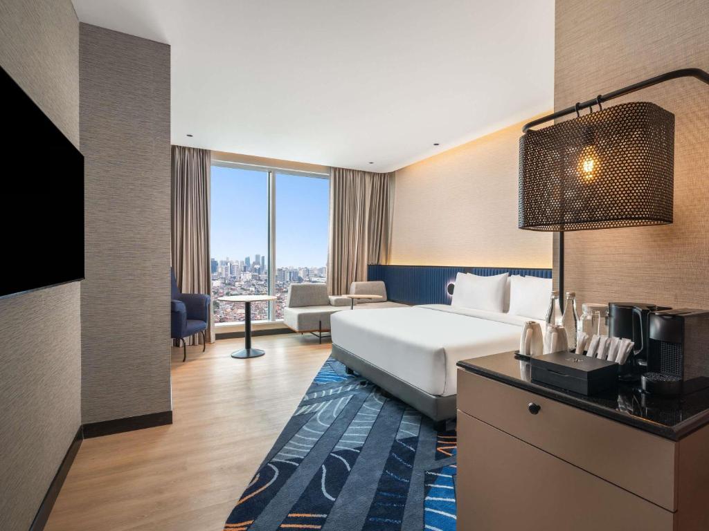 a hotel room with a bed and a couch at Novotel Jakarta Pulo Mas in Jakarta