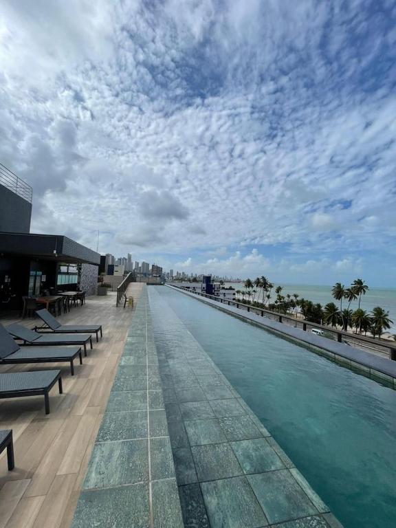 a swimming pool on the roof of a resort with the beach at Flat FM20 Apt 401 in João Pessoa
