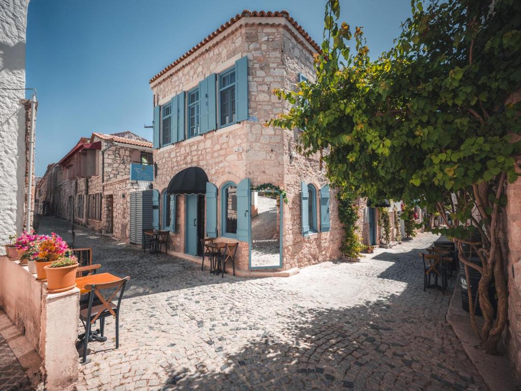 an alley with tables and chairs in front of a building at Casa Alegre Alaçatı in Alaçatı