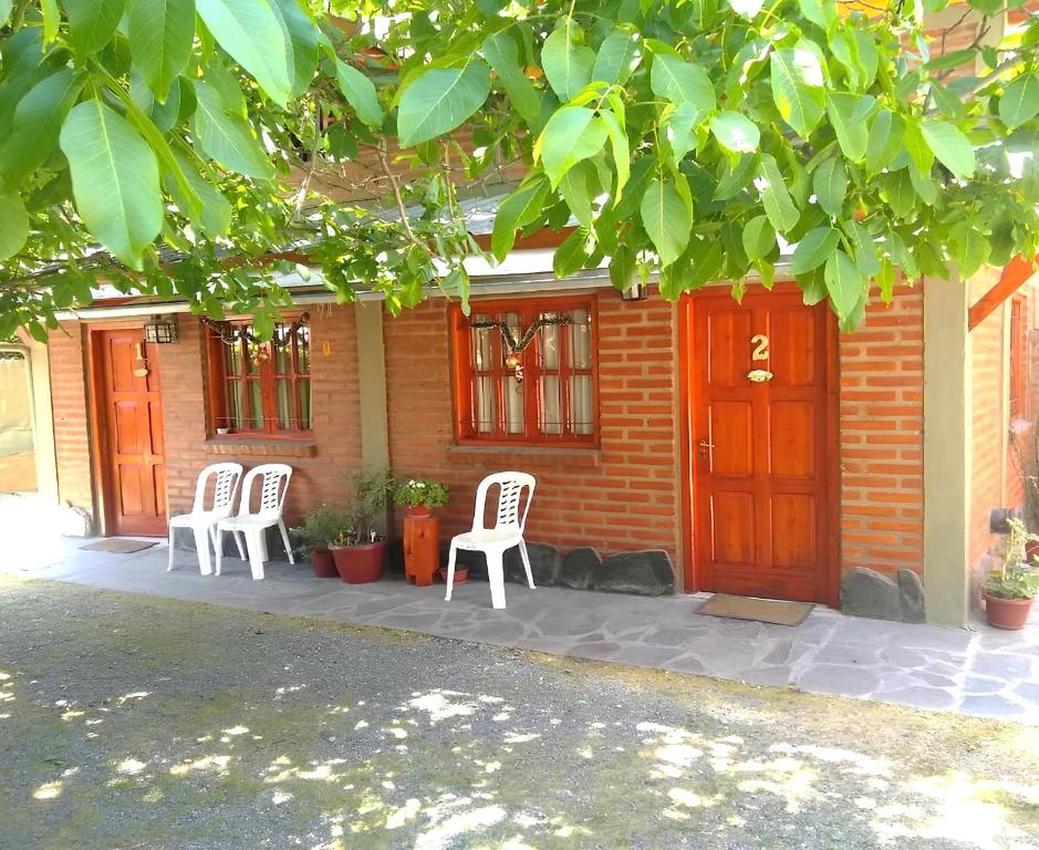 three white chairs sitting on a patio in front of a house at Cabañas Tunquelen in El Bolsón