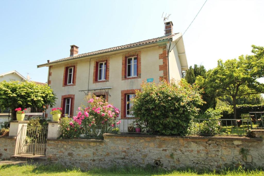a house with flowers in front of a stone wall at Boissac in Le Vigen