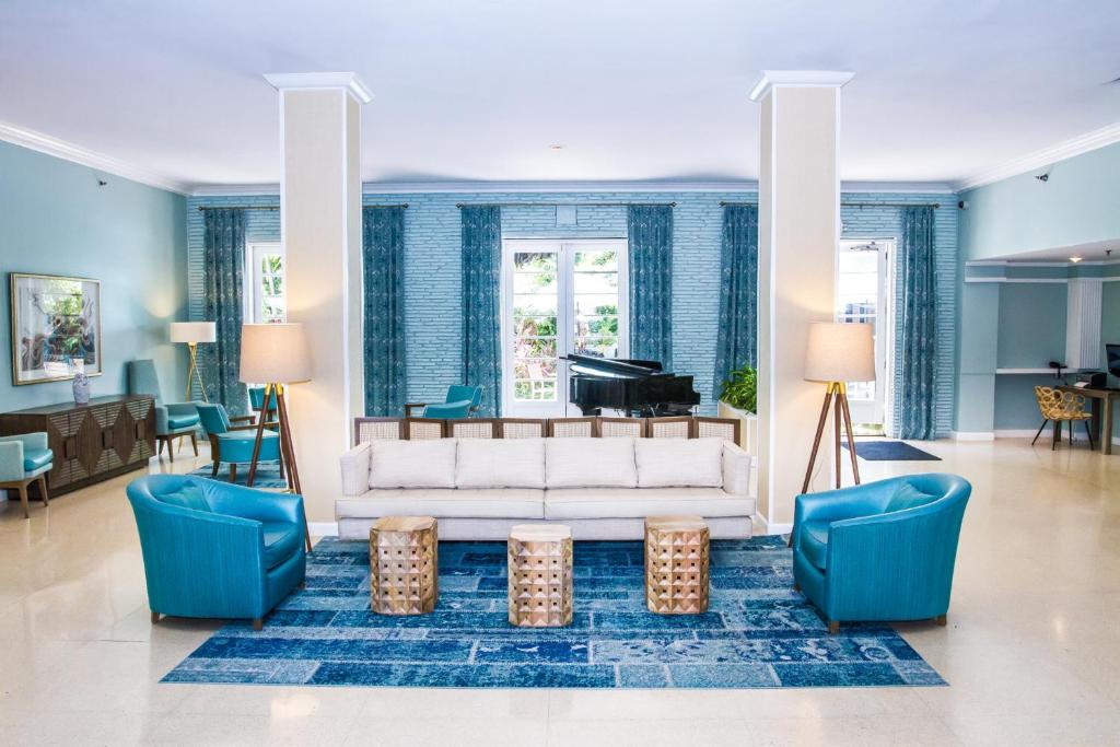 a living room with a white couch and a piano at Dorchester Hotel & Suites in Miami Beach