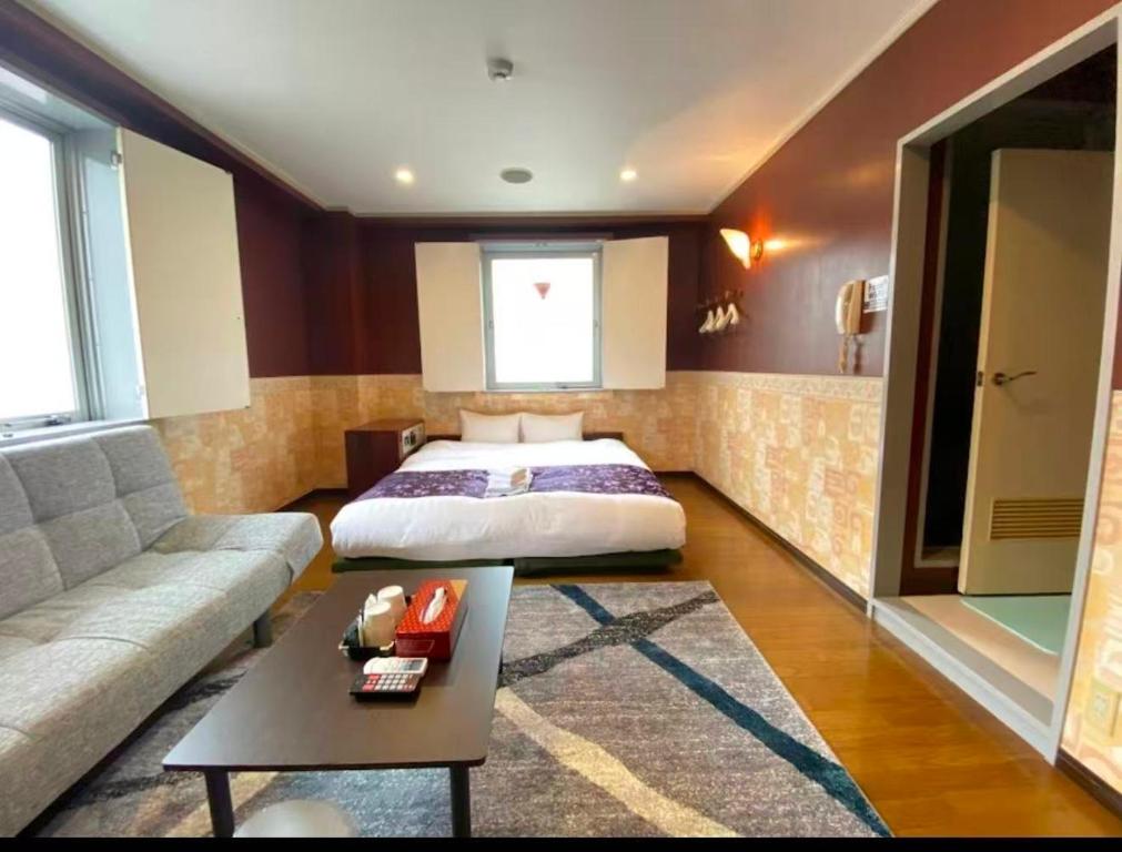 ein Schlafzimmer mit einem Bett, einer Couch und einem Tisch in der Unterkunft ホテルスズカ in Matsudo