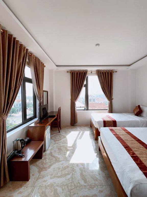 a hotel room with two beds and a desk at Flamengo hotel in Dong Hoi