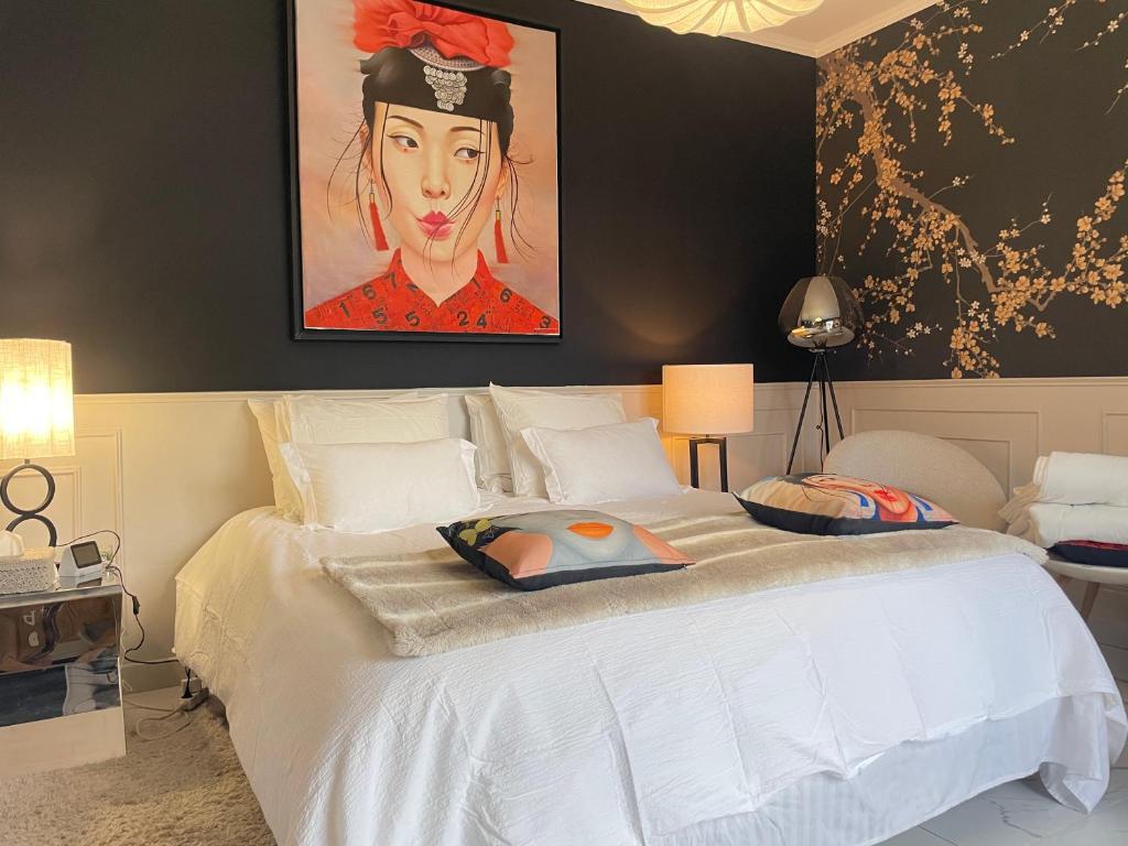 a bedroom with a white bed with a painting on the wall at Villa Bois d'Argent in Lagraulière