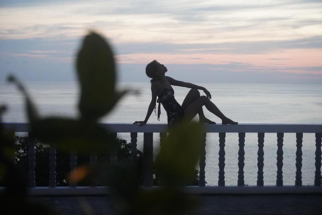 a woman sitting on a fence looking at the ocean at Residy Hideaway in Patong Beach