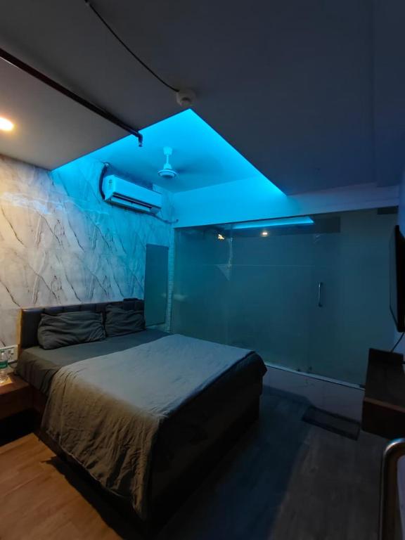 a bedroom with a bed with a blue light at Hotel The World in Surat