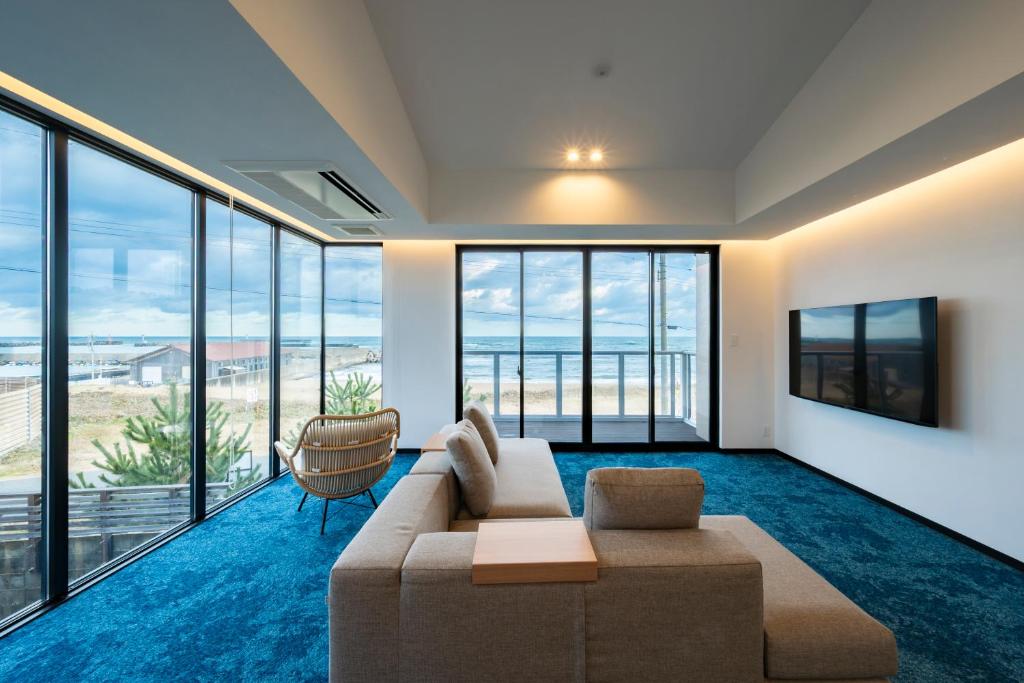 a living room with a couch and large windows at KITAMAE BASE Kaga Hashitate in Kaga