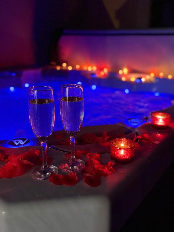 two wine glasses sitting on a table with candles at Sylina Spa avec Jacuzzi Privé in Villeblevin