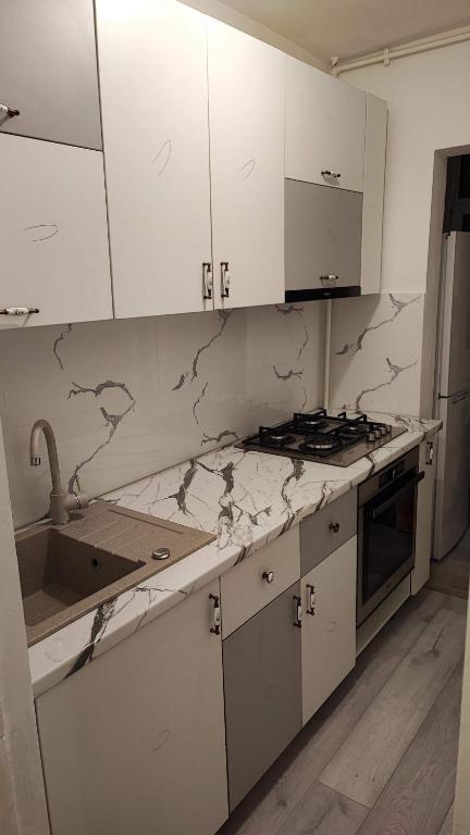 a kitchen with white cabinets and marble counter tops at Strand Apartament in Sibiu