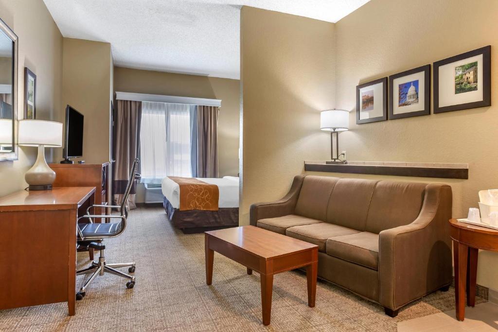 a hotel room with a couch and a bed and a desk at Comfort Suites Jonesboro University Area in Jonesboro