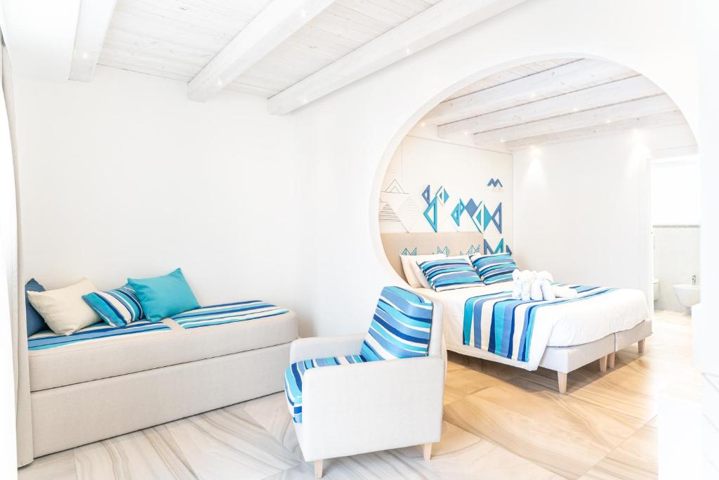 a white room with two beds and a chair at Luma Relais de Charme in Santa Teresa Gallura