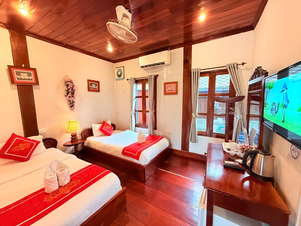 a room with two beds and a flat screen tv at Villa Ouis NamKhan River View in Luang Prabang