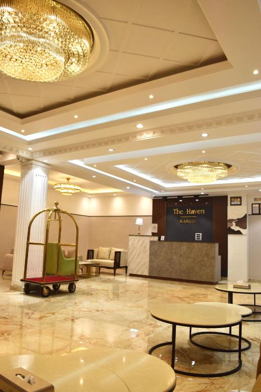 a hotel lobby with tables and a luggage cart at Hotel The Haven Kargil - Centrally Heated in Kargil