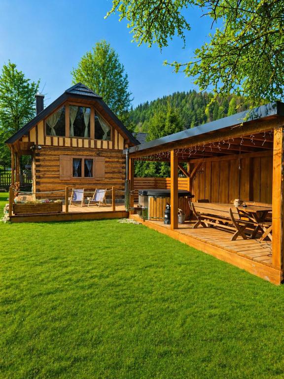 a log cabin with a porch and a green lawn at Drevenička Zázrivá Terchová in Zázrivá
