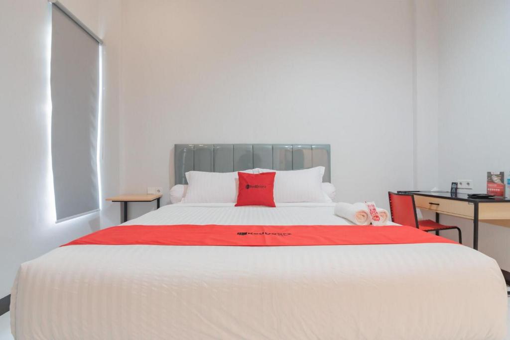 a bedroom with a large white bed with a red pillow at RedDoorz Plus near Siloam Hospital Balikpapan in Balikpapan