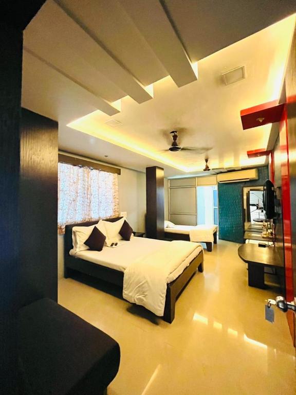 a bedroom with a large bed and a kitchen at Hotel MK in Ratlām