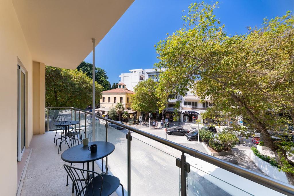 a balcony with tables and chairs on a city street at Folitsa happy central home in Rhodes Town