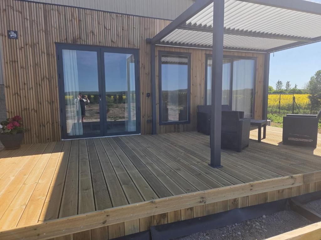 a wooden deck with glass doors and a bench on it at La roseraie in Abbécourt