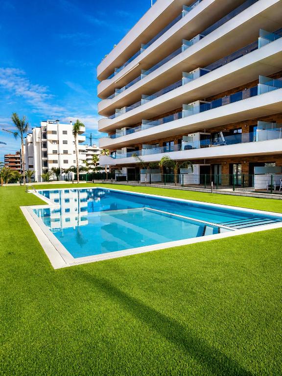 a swimming pool in front of a large building at Claudia Luxury Apartment near the beach with a pool, gym, and secure gated parking in Arenales del Sol