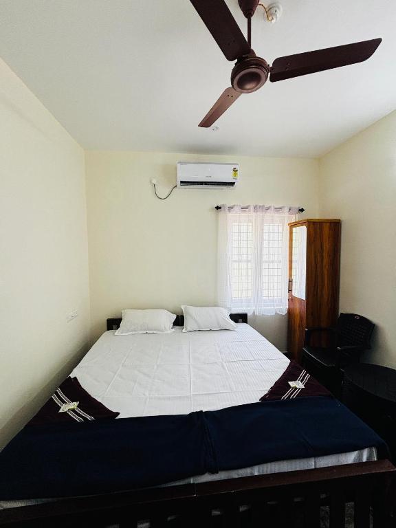 a bedroom with a bed with a ceiling fan at Babuloos Homestay in Varkala
