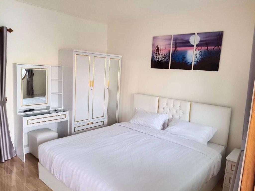 a white bedroom with a bed and a tv at Kasalong stay in Ban Nong Chaeng