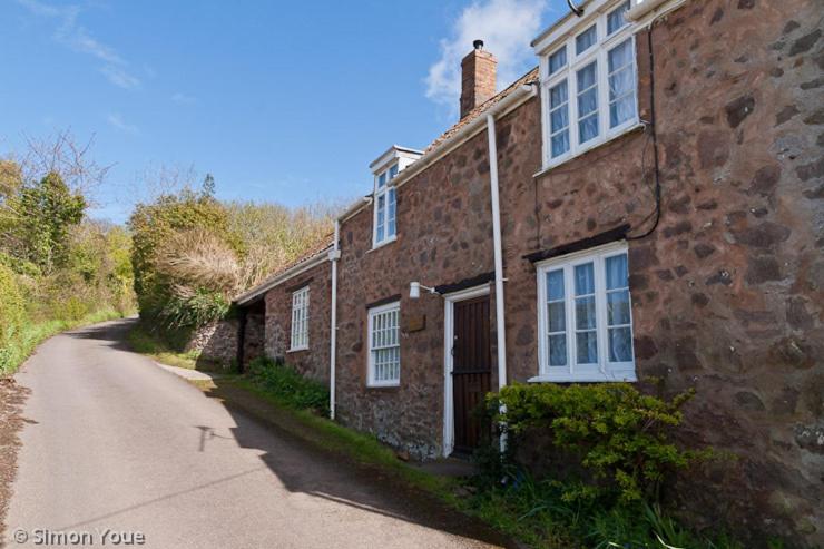 an old brick house with a road next to it at Moonfleat in West Quantoxhead