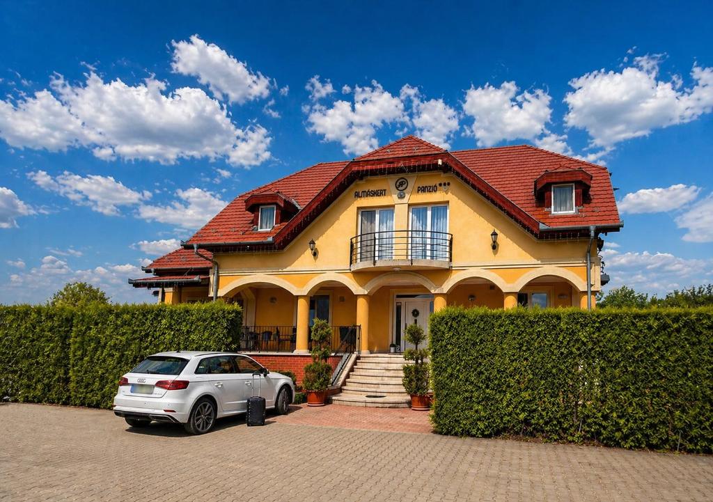 a yellow house with a car parked in front of it at Budapest Airport Almáskert Panzió in Vecsés