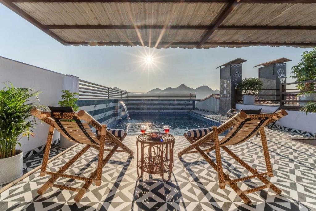 a patio with two chairs and a pool at MANGAL RESIDENCY Mountain View- A Luxury Boutique Business Hotel in Bedla