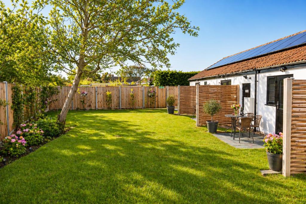 a backyard with a wooden fence and a tree at Lytton Tree Lodge Self-Catering Garden Lodges - Near Southwold in Reydon