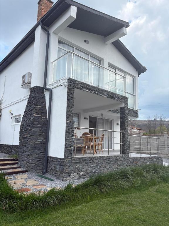 a white house with glass doors and a table at Trinity House in Obrochishte