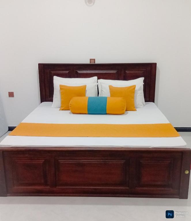 a bed with orange and blue pillows on it at Holiday Apartment Ragama in Kurukulawa