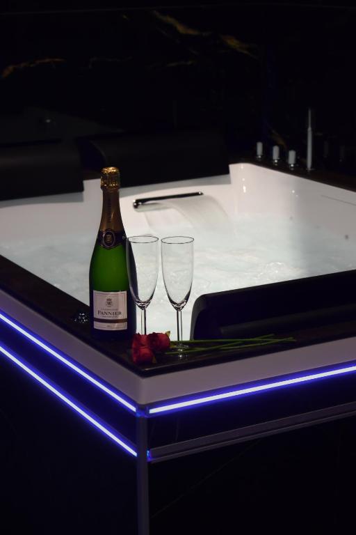 a bottle of wine and two glasses on a table at Hollywood Spa Jacuzzi - Cinéma in Château-Thierry