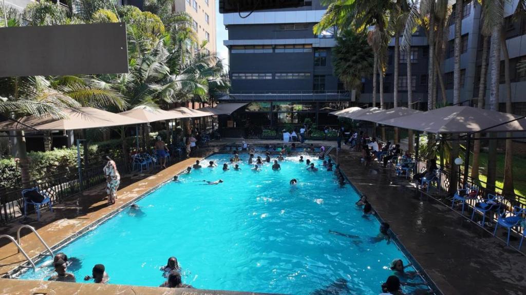 a group of people swimming in a swimming pool at The Luke Hotel - Roasters in Nairobi