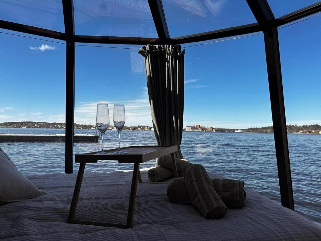 two wine glasses sitting on a table next to the water at Stockholm Archipelago Igloo Hut in Tynningö
