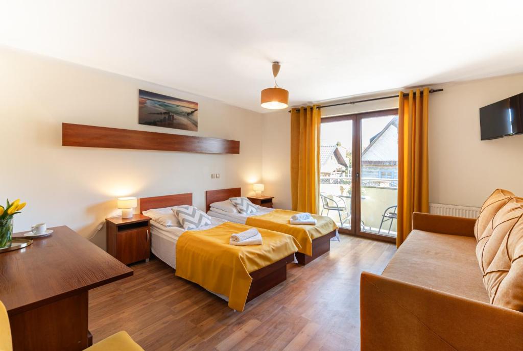 a hotel room with two beds and a couch at Gwarek Ośrodek nad Morzem Pokoje z wyżywieniem in Międzywodzie