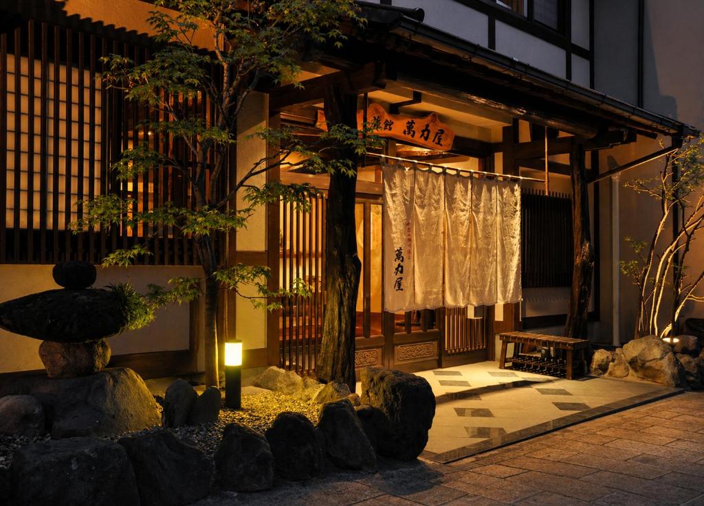 a building with a tree in the front of it at 全5室の小さな温泉旅館 別府鉄輪温泉 萬力屋 in Beppu