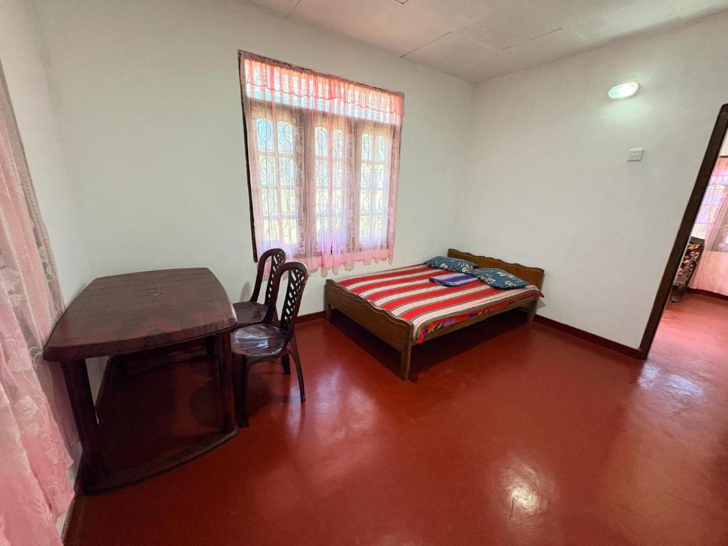 a room with a bed and a desk and a table at Hiker's Hub in Maskeliya