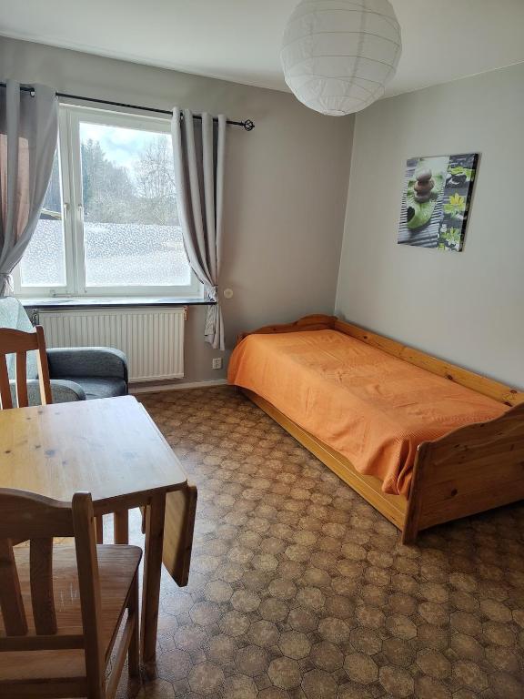 a bedroom with a bed and a table and a window at Bettan in Bruzaholm