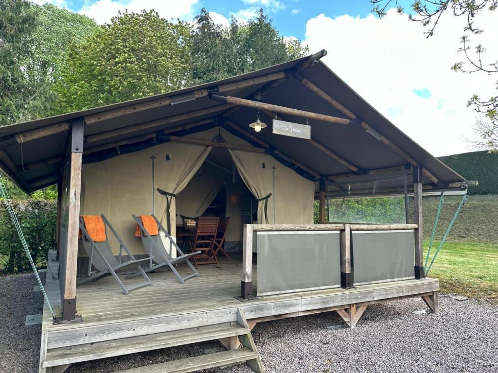 a tent with chairs on a wooden deck at Camping Le Sans Souci in Fresnay-sur-Sarthe
